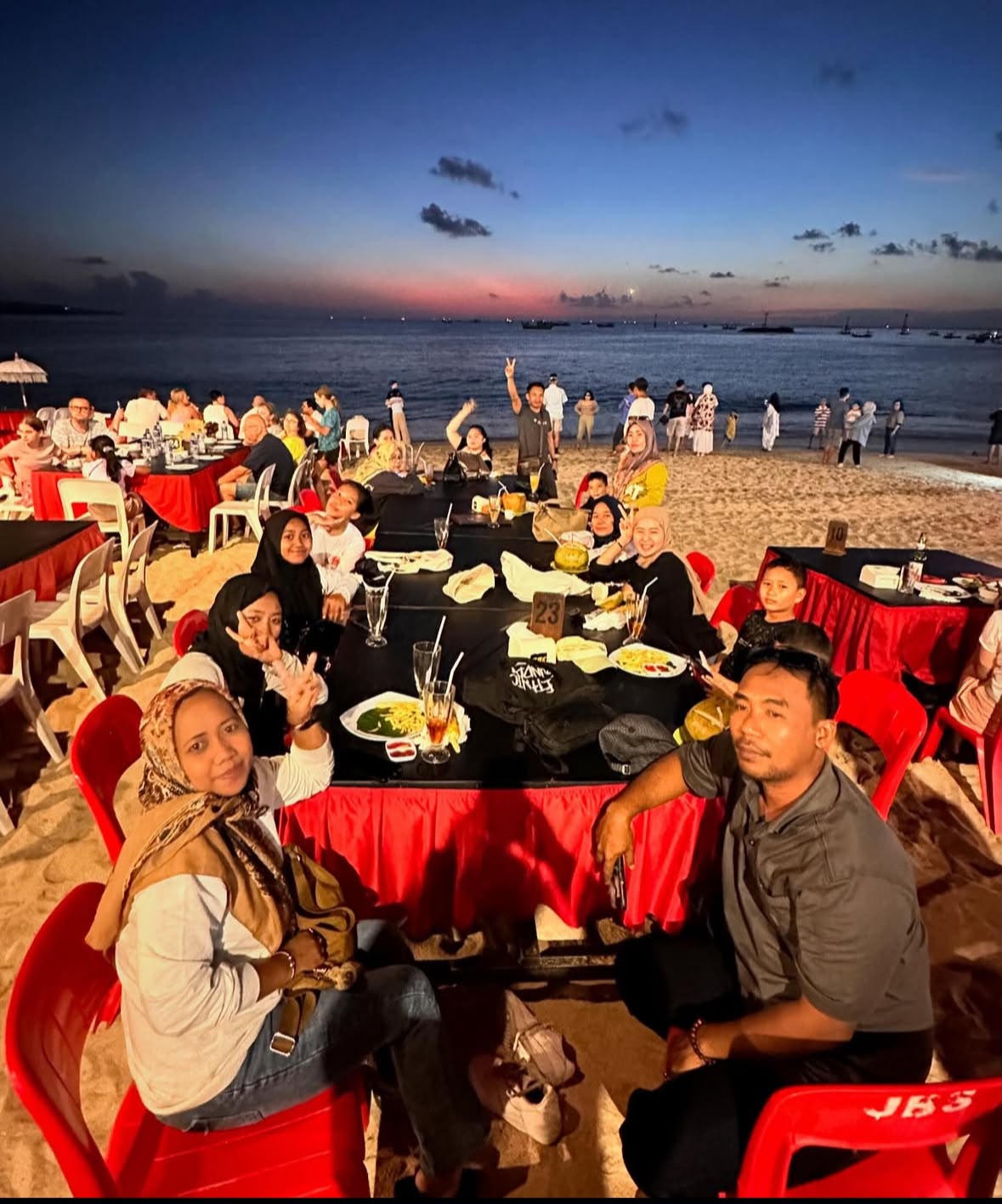 Group enjoying a beachfront sunset dinner